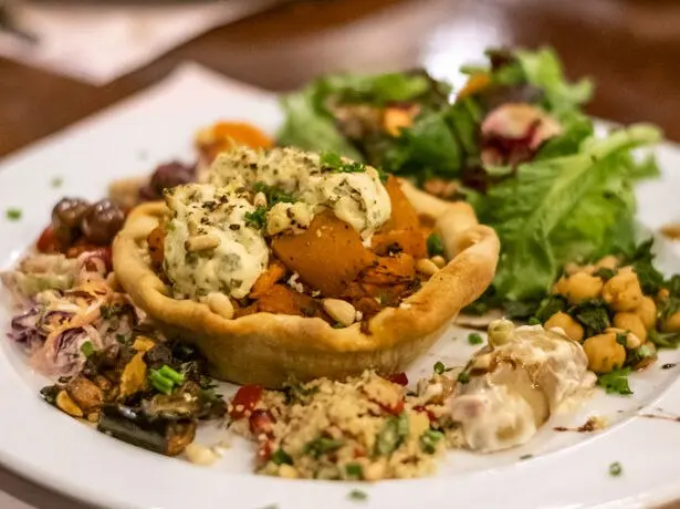 A plated meal with a pastry basket, vegetables and salad at Chicca’s