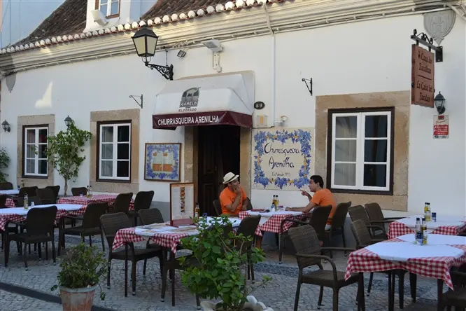 Tables outside the signed Churrasqueira Arenilha entrance on Rua Almirante Cândido dos Reis.