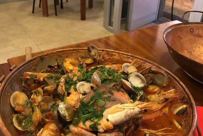 An open copper cataplana filled with seafood and herbs, from Copos & Petiscos’ own food gallery.