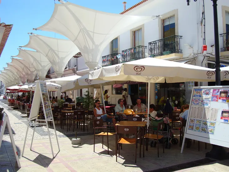 Outdoor café tables under umbrellas outside the Coração da Cidade branch on Rua Dr. Teófilo Braga.