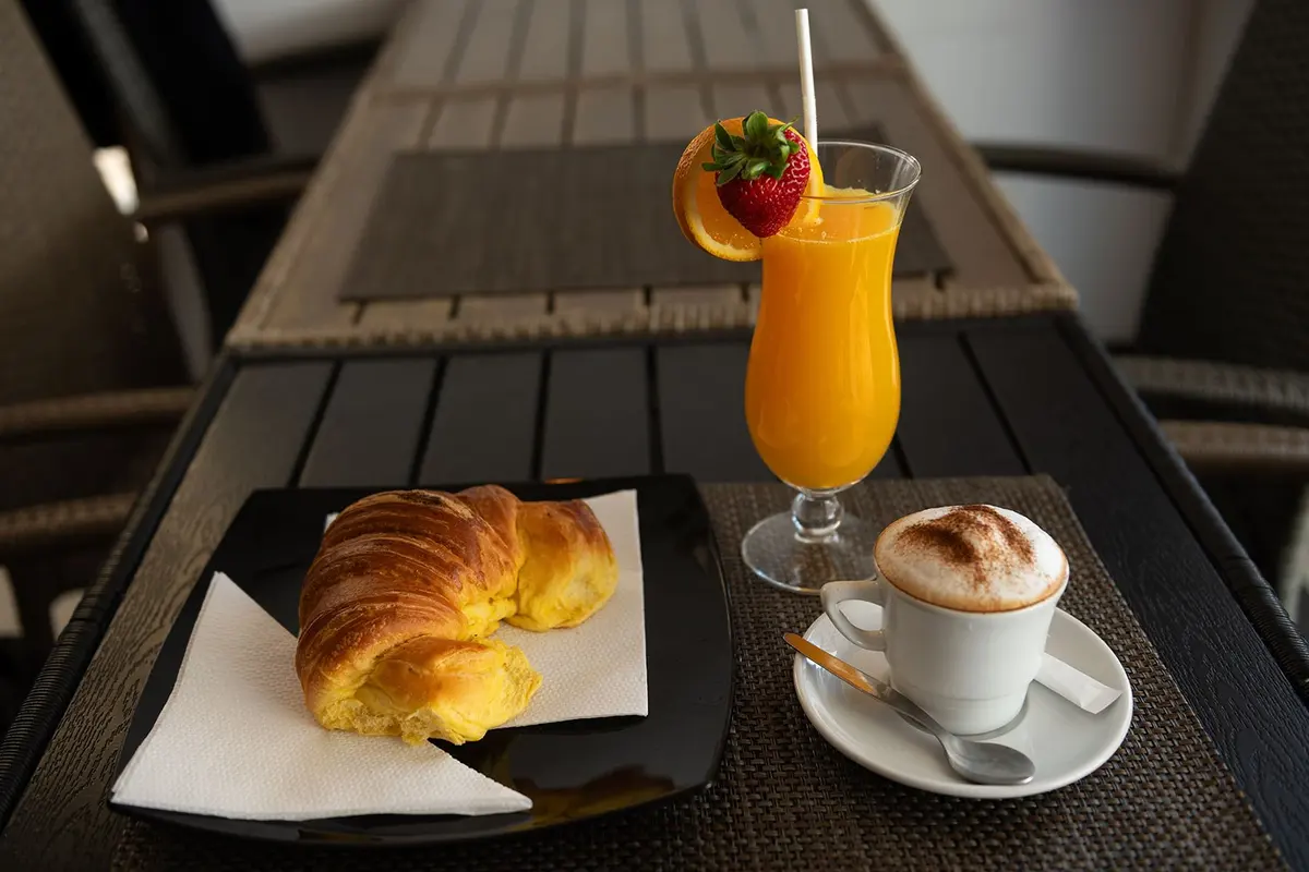 Croissant, cappuccino and juice on a café table at D’Maria