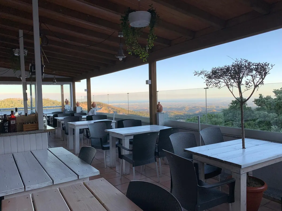 Tables beneath the covered terrace at Luar da Fóia with the hills and coast beyond