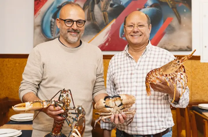 Two men holding crabs inside Marisqueira Rui in Silves