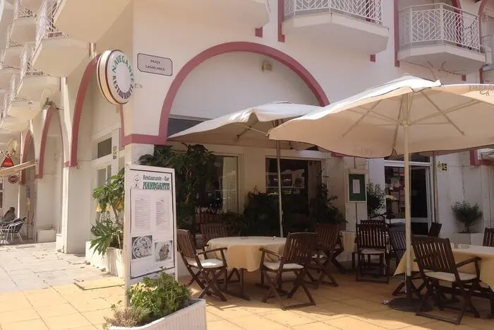 Outdoor tables and umbrellas beside the Navegante restaurant entrance in Monte Gordo.