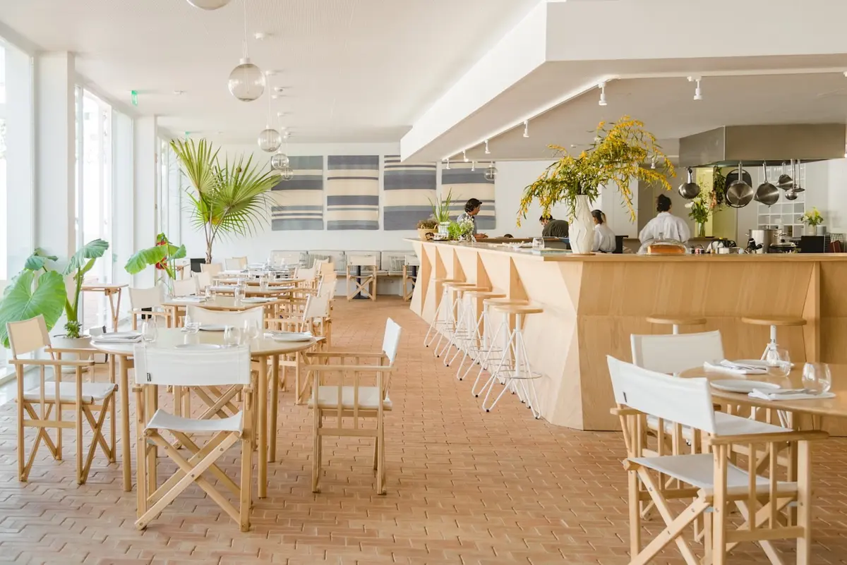 Bright dining room, wooden tables and bar at Orta in Casa Mãe