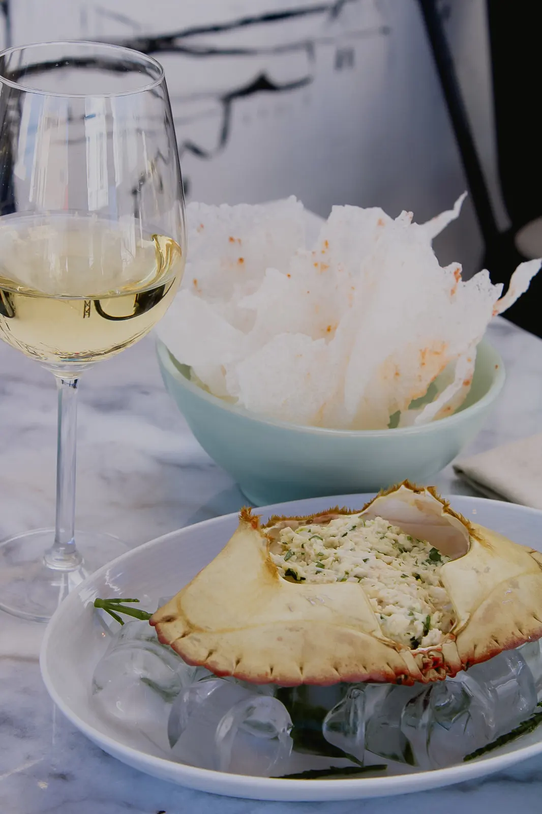 A stuffed crab shell, crisp accompaniments and a glass of white wine from Ostra Uva’s own food gallery.