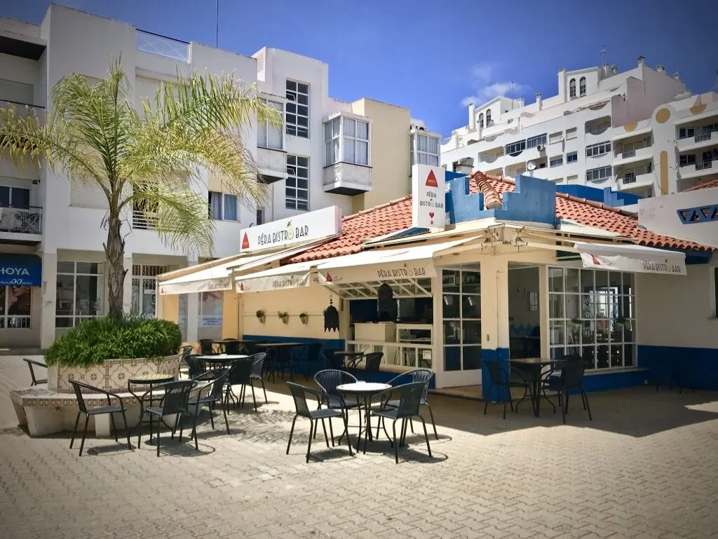Outdoor tables and the entrance of Pêra Bistro Bar beside Armação de Pêra’s municipal market