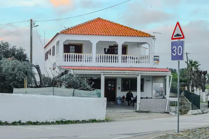 The white building and ground-floor entrance of Pastelaria Snack Bar O Poço Novo in Giões.