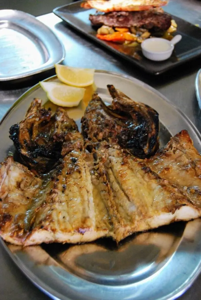 Whole grilled fish served with vegetables and lemon at Retiro do Pescador