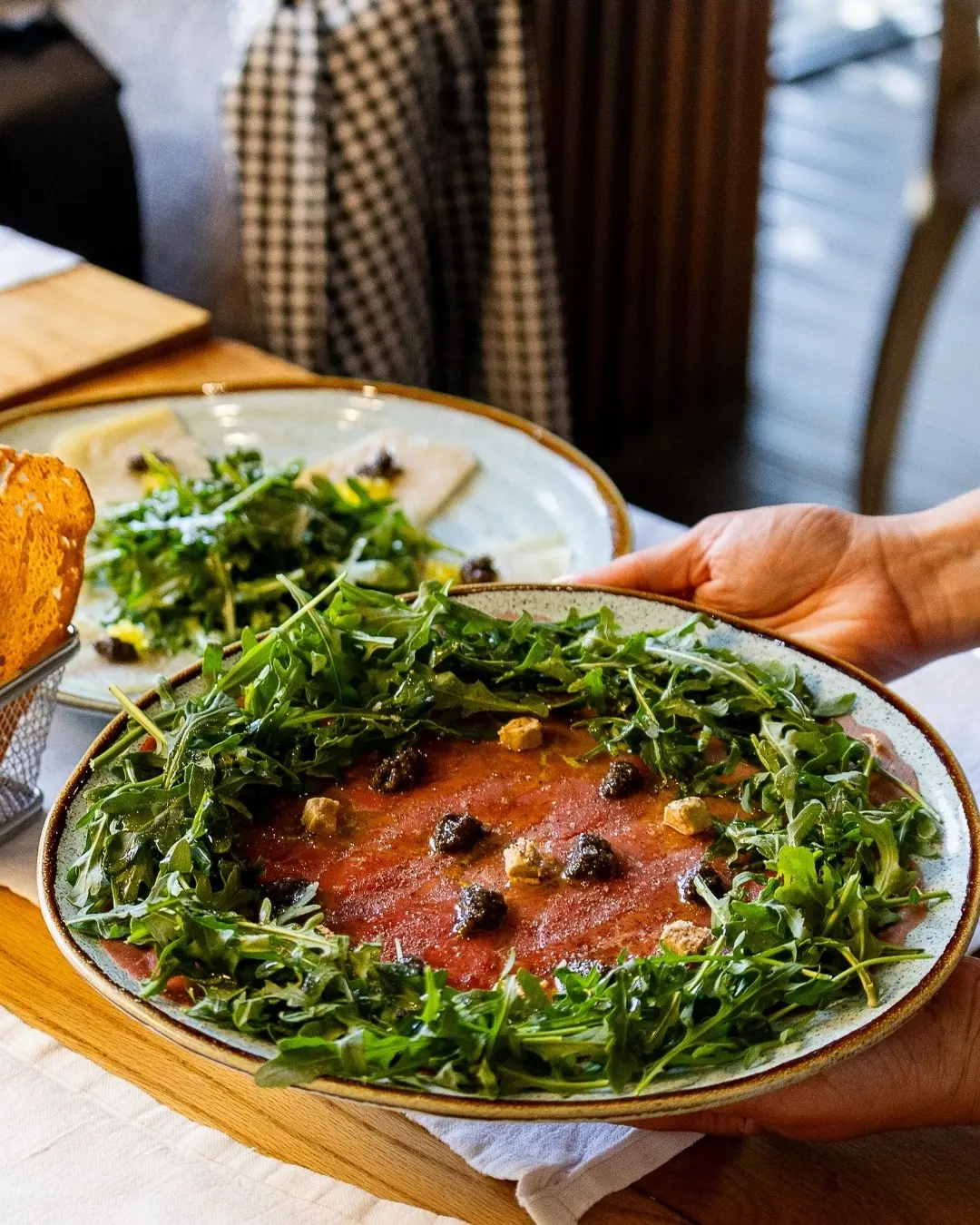 A plated dish surrounded by green leaves being served at Salmora in Vilamoura