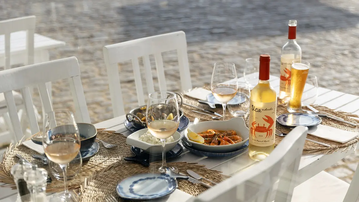 Small plates and glasses on an outdoor Sueste table beside the Arade in Ferragudo