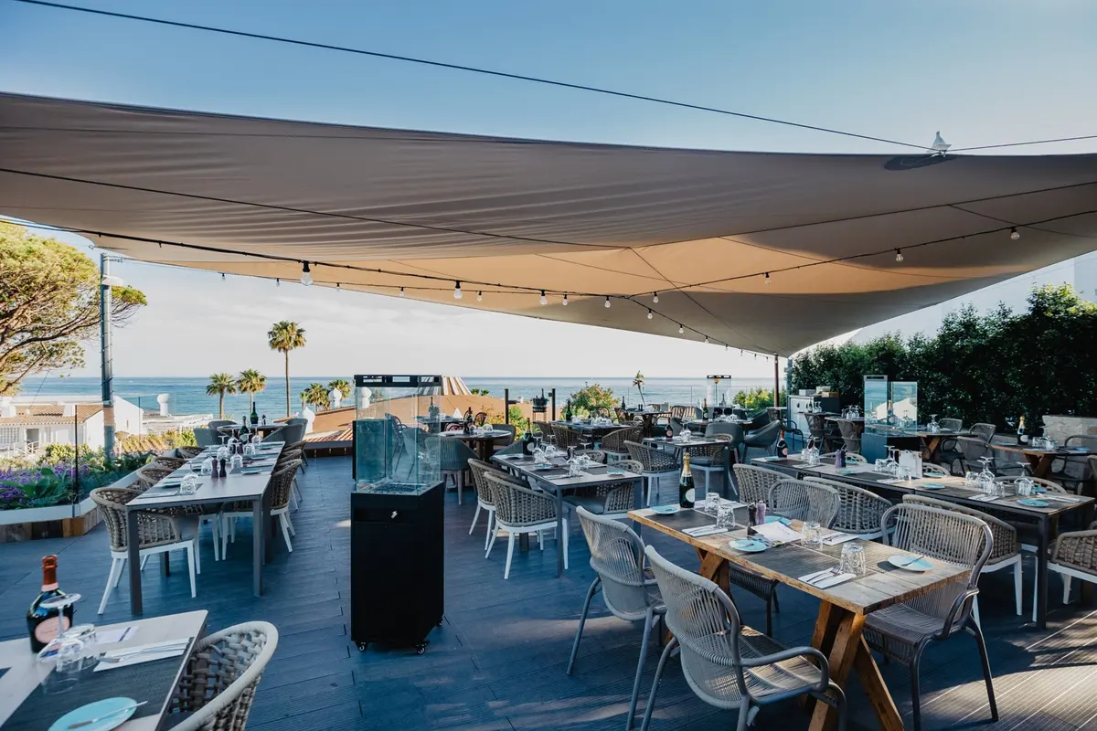 Restaurant tables beneath a canopy looking towards the sea at U&Co in Vale do Lobo
