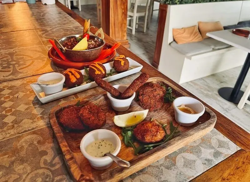 Boards of golden patties, sauces and garnishes on a tiled restaurant counter