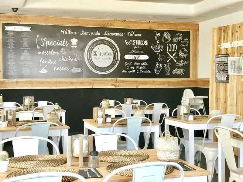 White tables and chairs beneath @Willem’s large chalkboard wall in Monte Gordo.