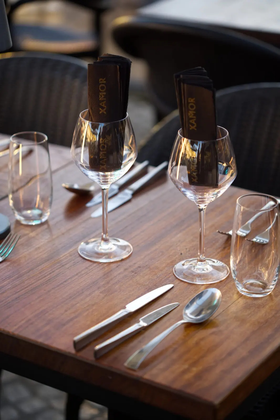 Wine glasses and place settings on a wooden table at Xamor in Carvoeiro