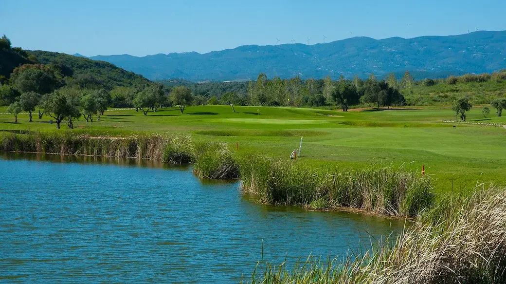 A lake, golf green and wooded hills at Álamos Golf