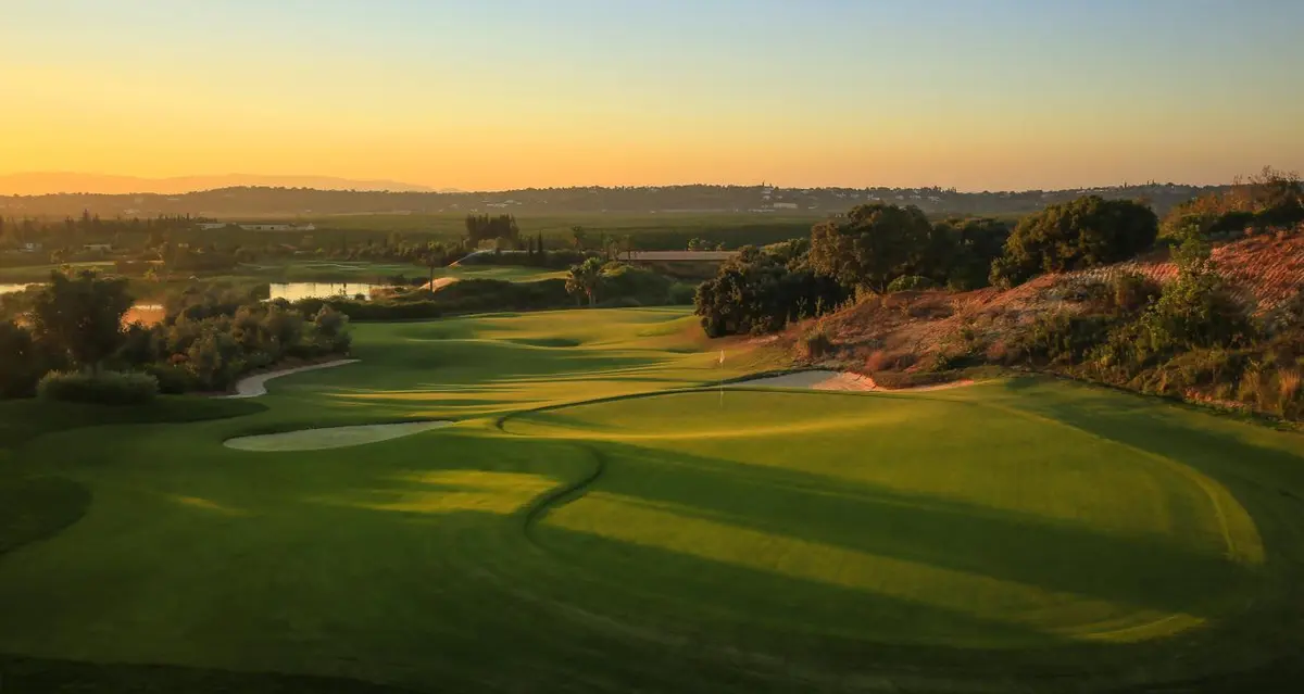 A green, bunker and rolling fairway at sunset on Amendoeira’s O’Connor Jnr Course