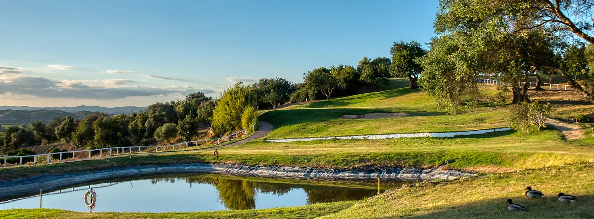 A pond, bunker and hillside green at Benamor Golf