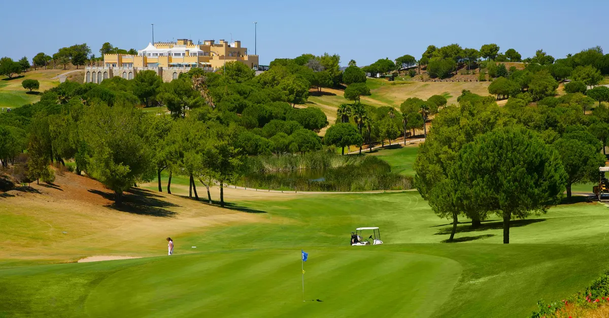 A golf green, wooded fairways and the hilltop clubhouse at Castro Marim Golfe