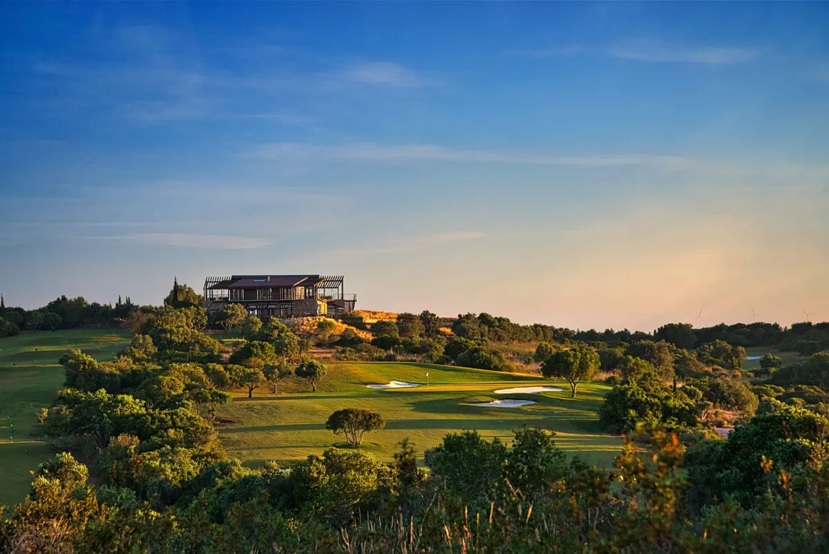 A green and white bunkers below the hilltop clubhouse at Espiche Golf