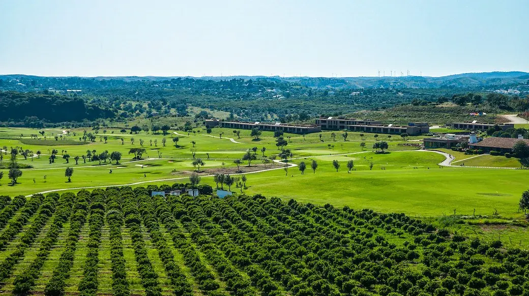 Fairways, greens and resort buildings at Morgado Golf with orchards in the foreground