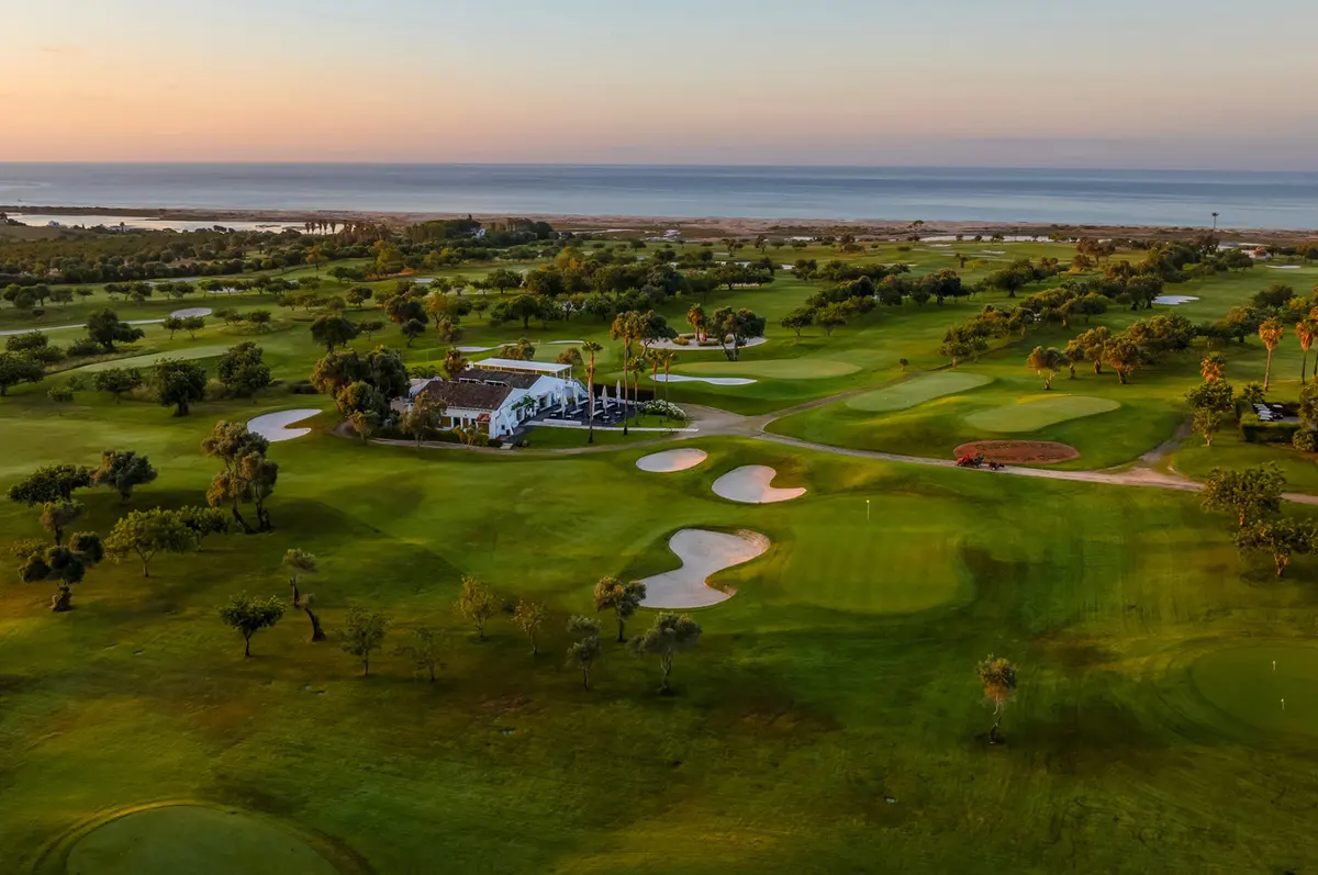 Aerial view across Quinta da Ria’s greens and clubhouse towards the Ria Formosa and sea