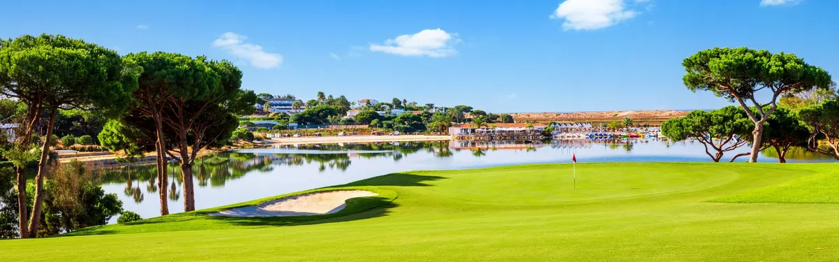 A green, bunker and umbrella pines beside the lake on Quinta do Lago’s South Course