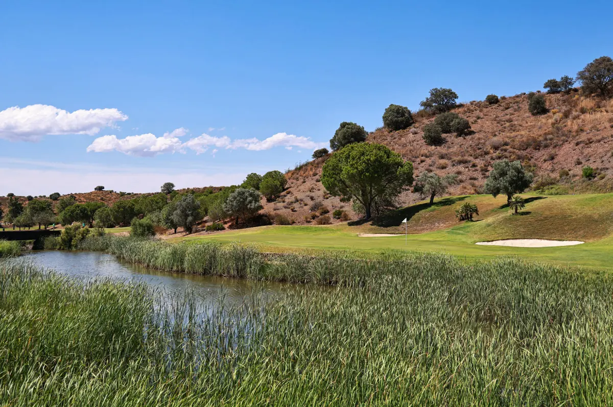 A lakeside green and bunker below a hillside on Quinta do Vale’s first hole
