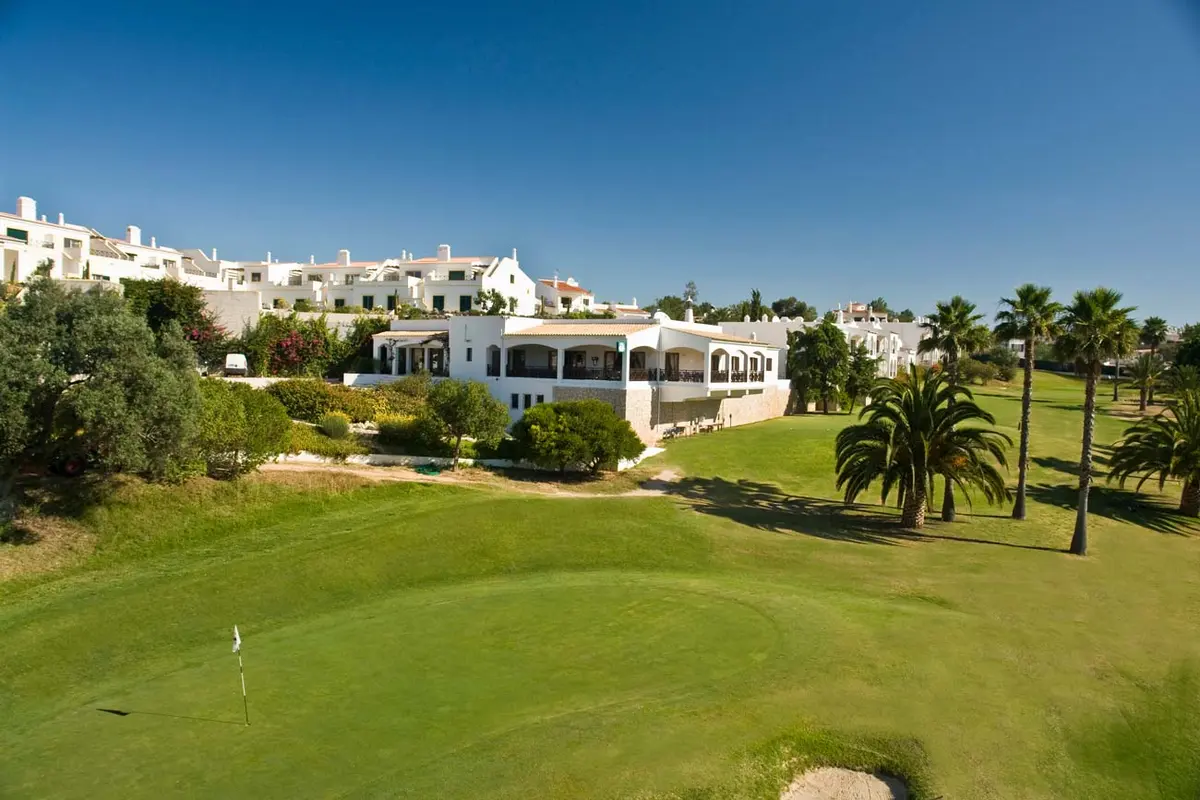 A green and palm trees below the clubhouse at Vale de Milho Golf
