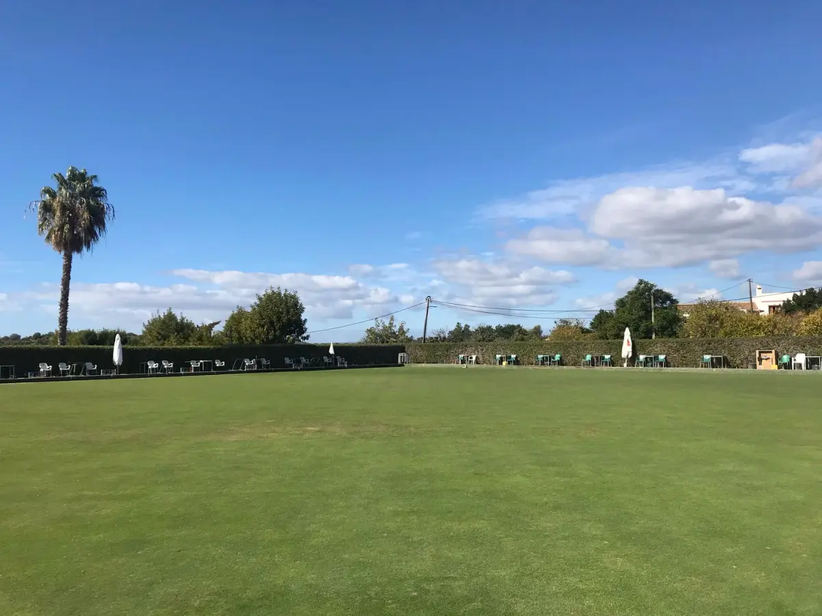 The lawn-bowls green at Alvor Bowls Club with chairs around its edge