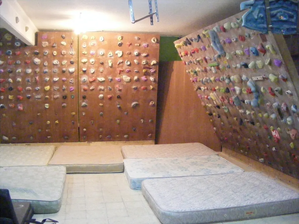 An indoor bouldering room with colourful holds and floor mats
