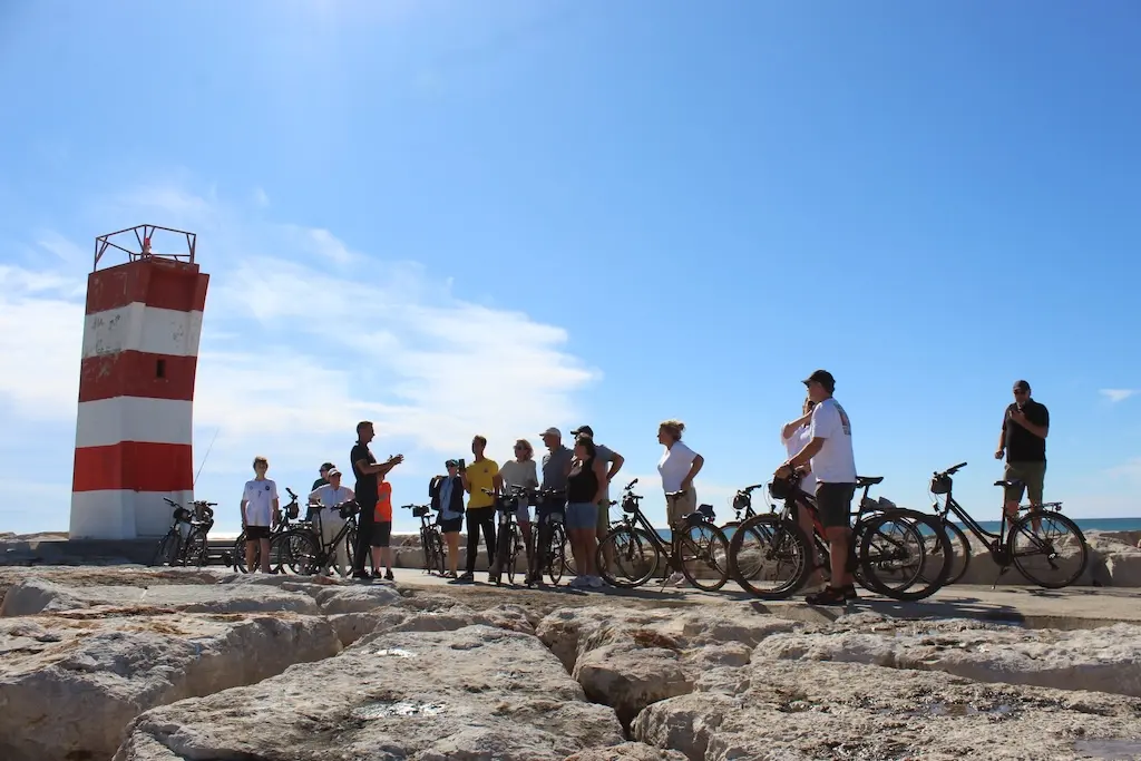 A group with bicycles beside the red-and-white harbour beacon in Vilamoura