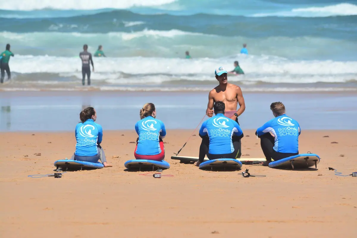 An instructor speaking to seated Boa Onda students beside their boards