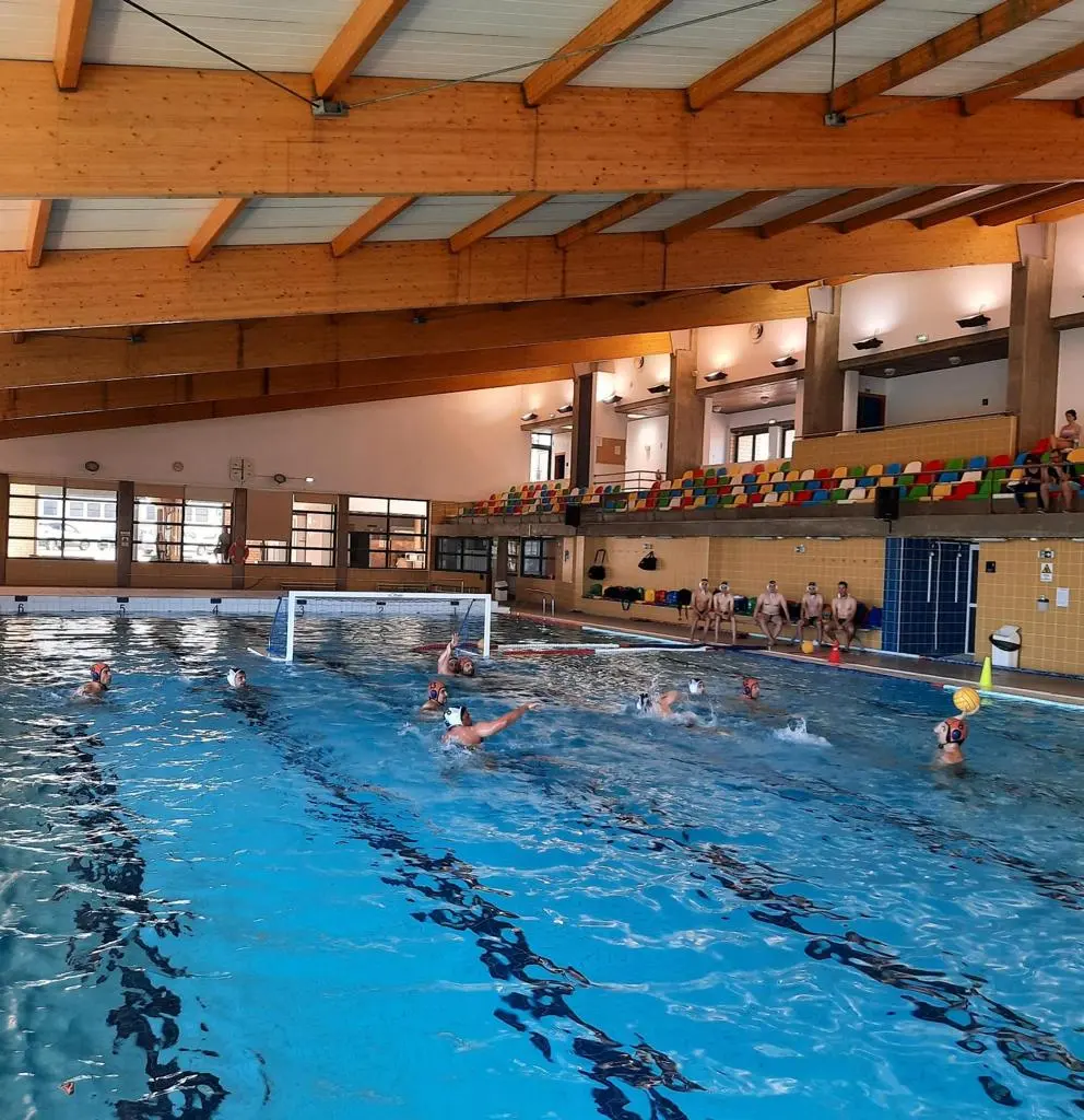 Water-polo training inside Lagoa Municipal Pool beneath a timber roof