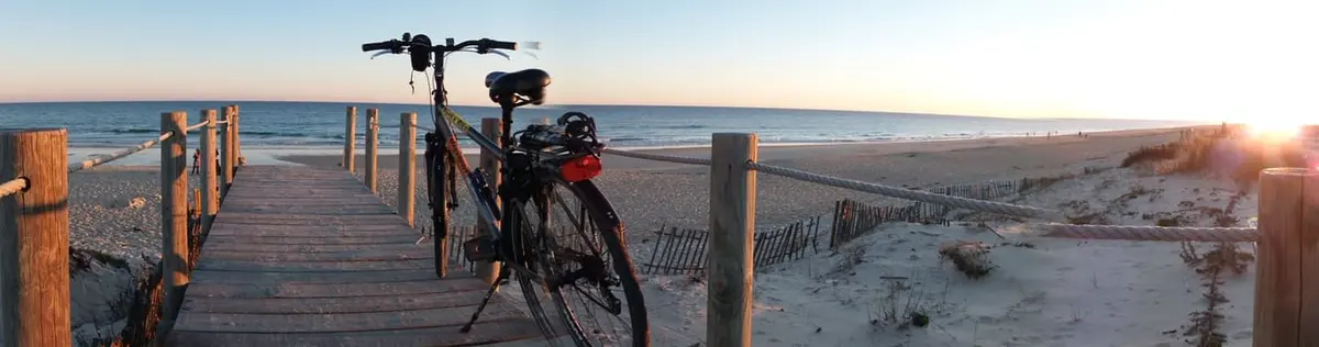A bicycle beside a wooden beach boardwalk at sunset