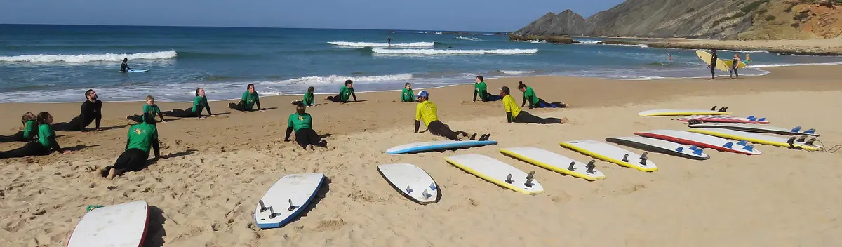 A surf group stretching beside boards on Odeceixe beach