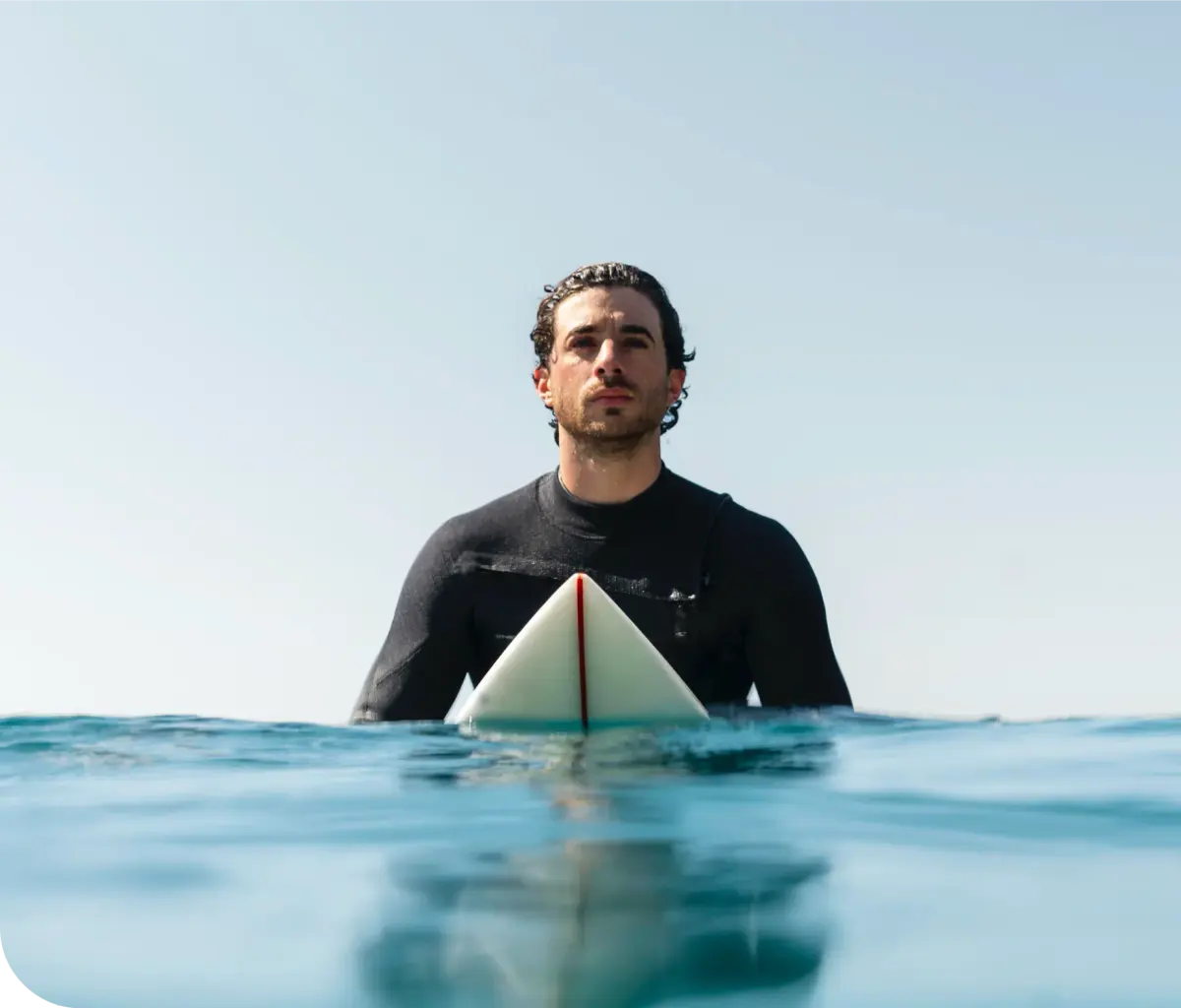 A surfer with a board looking towards the sea from the water