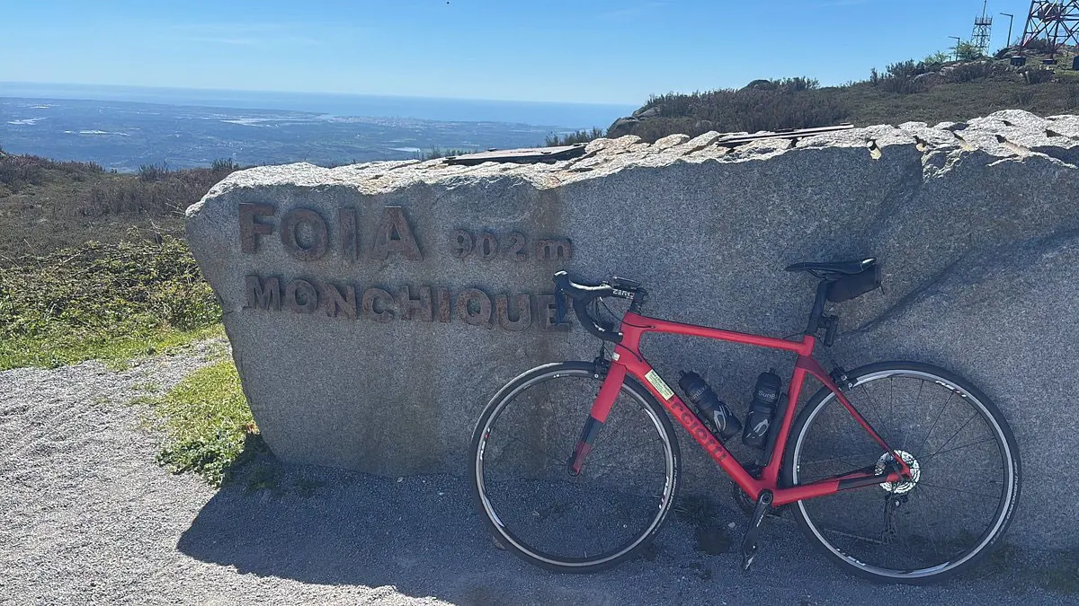 A red road bicycle beside the Fóia summit marker in Monchique