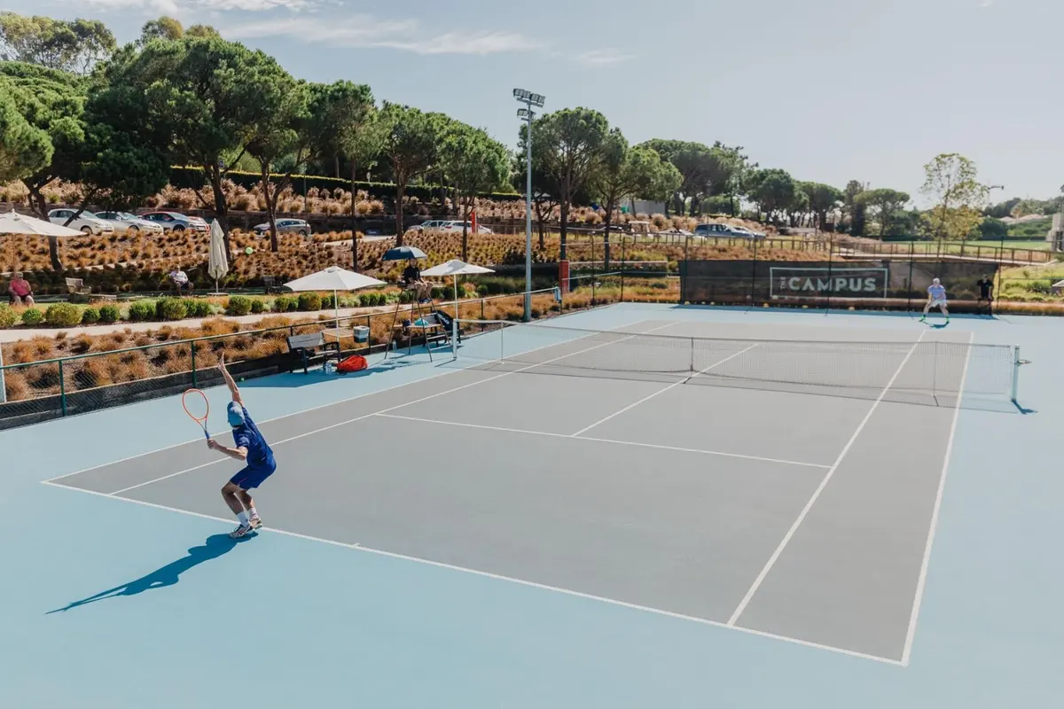 Players on a blue tennis court with The Campus branding on the far fence