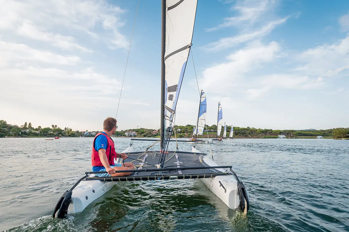 A sailor on a small catamaran with other sailing boats on Quinta do Lago lake
