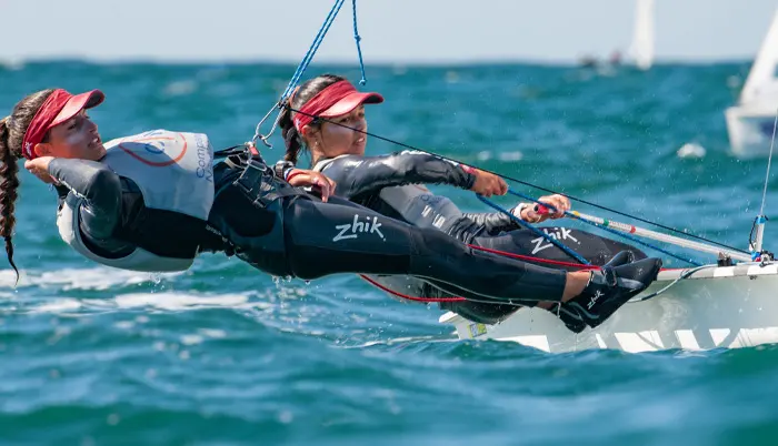 Two dinghy sailors leaning out over the water in CIMAV’s sailing-school photograph