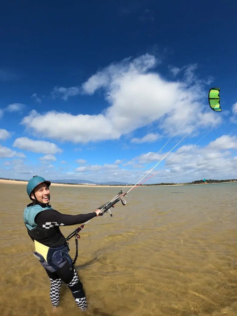 A helmeted participant practises kite control in shallow water