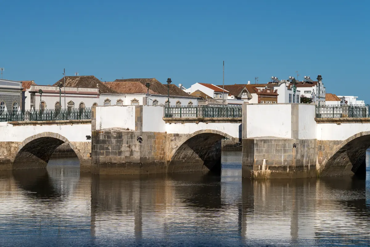 The old white bridge reflected in the River Gilão in Tavira
